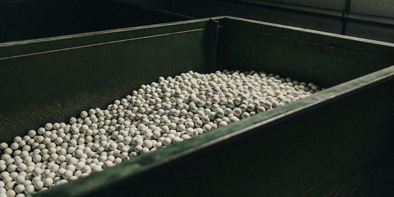 A pile of white activated alumina balls on a clean industrial surface