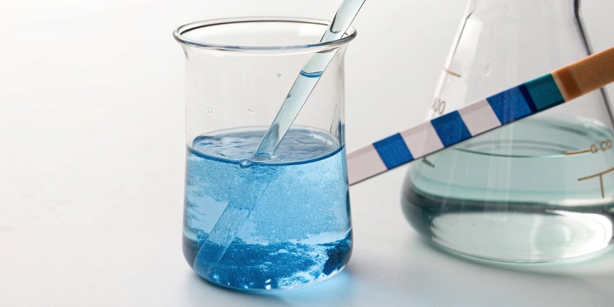 alt with keywords: A beaker of water with a pH strip turning blue, indicating an alkaline solution.