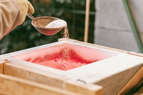 alt with keywords: A spoonful of salt being sprinkled over molten aluminum in a crucible to act as a flux