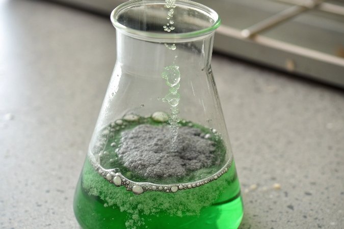 alt with keywords: A beaker of green chromium solution with a grayish-green precipitate forming as a base is added.