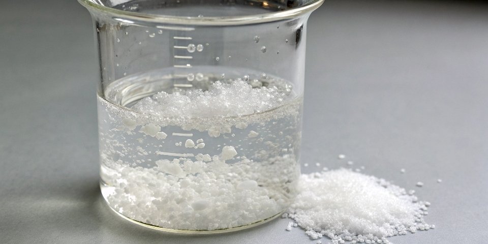 Solubility of Aluminum Nitrate A beaker of clear water with white Al(NO3)3 crystals dissolving completely at the bottom