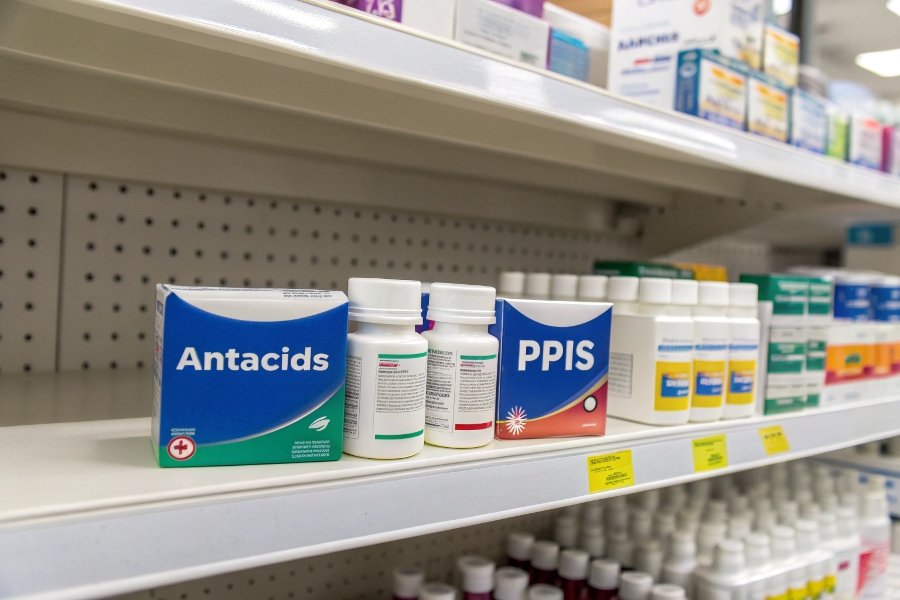 alt with keywords: A pharmacy shelf showing antacids in one section and other stomach medicines like PPIs in another.