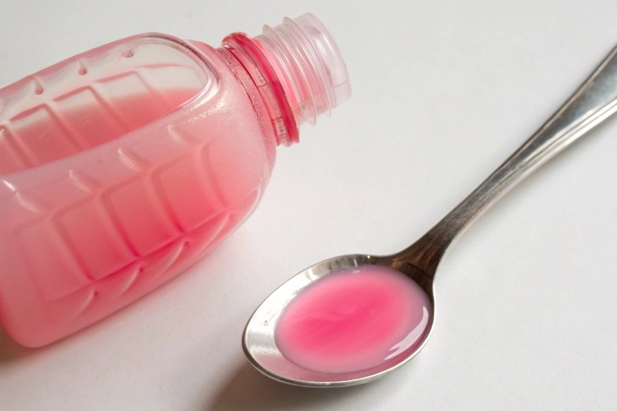 alt with keywords: The famous pink bottle of Pepto-Bismol next to a spoon with the pink liquid.