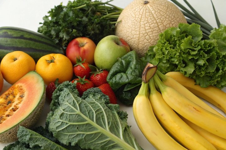 A colorful arrangement of fruits and vegetables like bananas, melons, and leafy greens