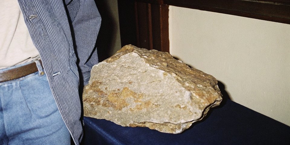 A close-up photo of raw bauxite ore, showing its reddish, earthy, and rock-like texture