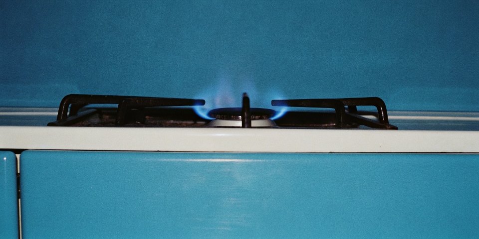 A close-up of a blue flame from a natural gas burner on a stove