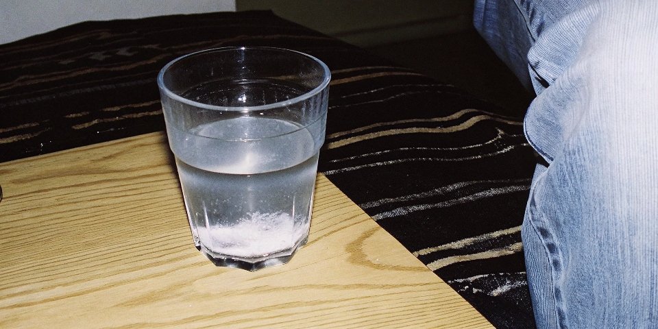 A clear glass of water with white aluminum hydroxide powder settled at the bottom, showing no reaction