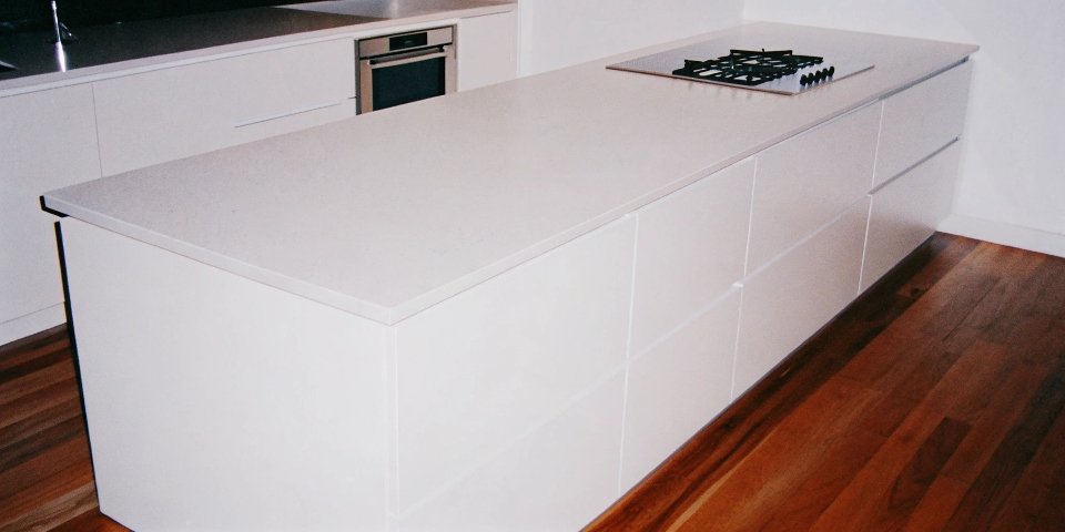 A modern kitchen with a clean, white solid surface countertop made with aluminum hydroxide filler