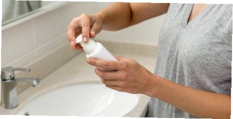 A person applying roll-on deodorant.