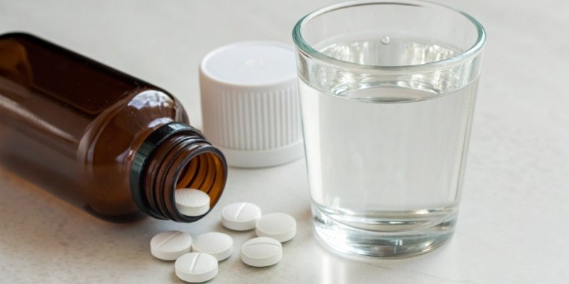 A bottle of antacid tablets next to a glass of water