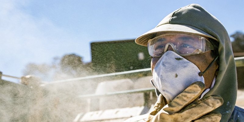 A worker wearing a dust mask and safety glasses in a dusty environment